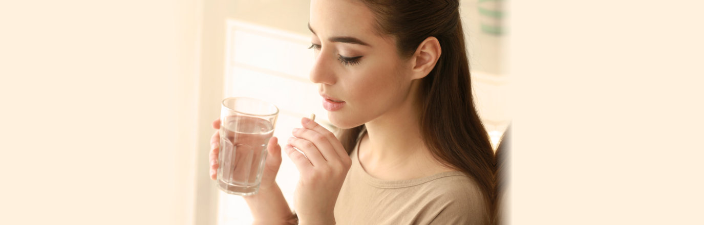 young woman taking pill at home